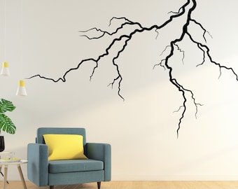 May include: A living room interior design with a teal armchair and a yellow throw pillow. The wall is decorated with a black silhouette of a tree branch.