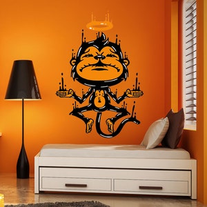 May include: Black and orange wall decal of a cartoon monkey with a halo, meditating with its arms outstretched. The monkey is dripping with black liquid, creating a unique and whimsical design.