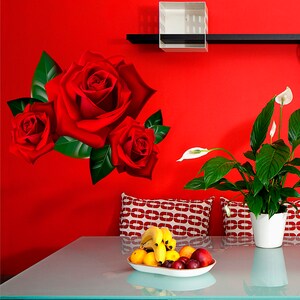 Puede incluir: Una pared roja con un estante y una caja blanca en &eacute;l. Hay tres rosas rojas en la pared. Una planta en maceta con flores blancas est&aacute; en el lado derecho de la imagen. Una mesa de vidrio con un taz&oacute;n de fruta est&aacute; en primer plano.