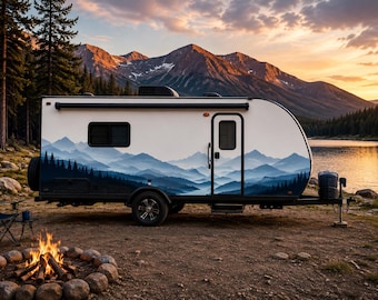 May include: A white travel trailer featuring a blue mountain and forest graphic wrap on its side, equipped with a single door, a rectangular window, and black wheels, positioned outdoors near a campfire and a lake with mountains in the background.