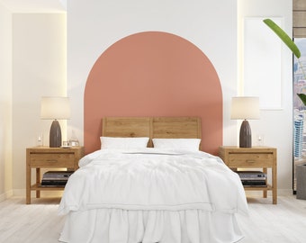 Puede incluir: Una cama blanca con una cabecera de madera y una pared de acento de medio círculo de color melocotón. Dos mesitas de noche con lámparas están a cada lado de la cama.