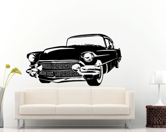 May include: Black and white silhouette of a classic car, a vintage saloon with a long bonnet and large headlights. The car is facing the viewer and is set against a white background.
