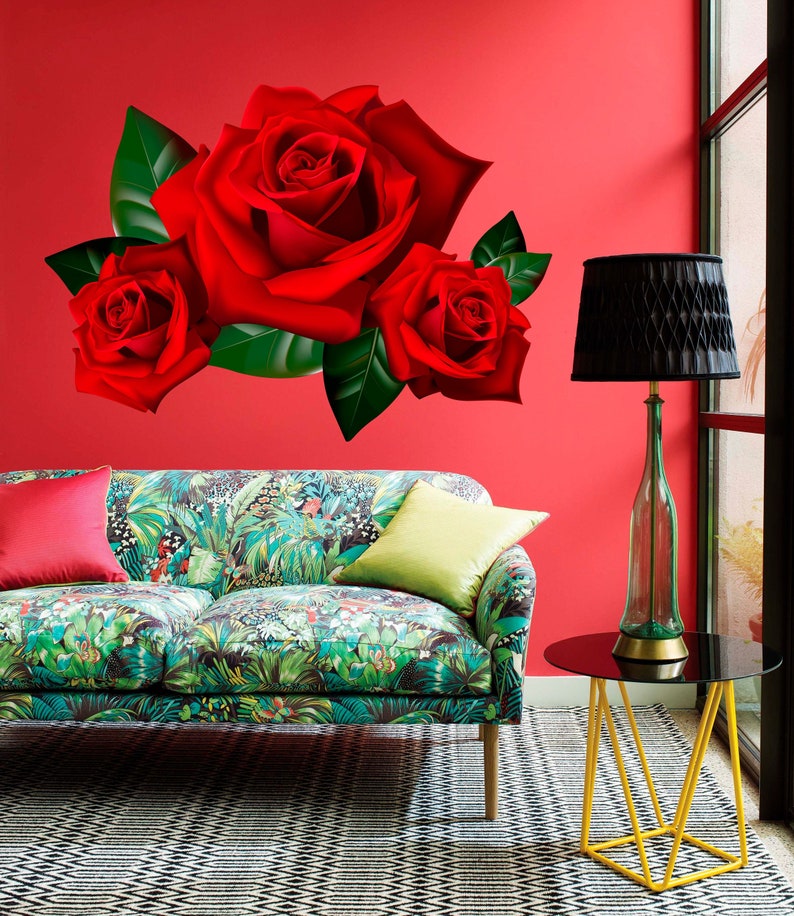 Puede incluir: Un adhesivo de pared floral rojo con tres rosas grandes y hojas verdes. El adhesivo est&aacute; colocado en una pared roja sobre un sof&aacute; estampado en verde y marr&oacute;n con un coj&iacute;n verde y un coj&iacute;n rojo.