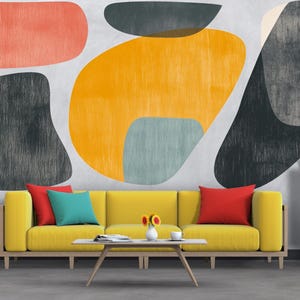 Puede incluir: Un salón moderno con un sofá amarillo, cojines coloridos y una mesa de centro blanca. La pared presenta un diseño abstracto con formas naranjas, amarillas, grises y turquesas. Un armario blanco y plantas en macetas completan la escena.