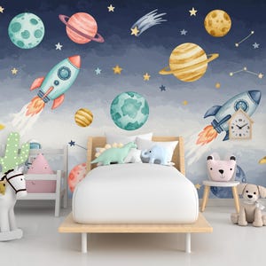 Könnte beinhalten: Kinderzimmer mit einem Weltraum-Themen-Wandbild mit Planeten, Raketen und Sternen. Das Zimmer umfasst ein Bett mit Dinosaurierkissen, ein Schaukelpferd und einen kleinen Stuhl mit einem bärenförmigen Kissen. Das Farbschema ist hauptsächlich blau, weiß und gelb.