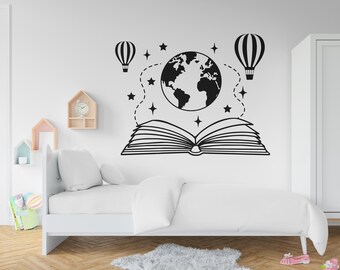 Puede incluir: Pegatina de pared en blanco y negro con un libro abierto, un globo terráqueo y dos globos aerostáticos. El diseño incluye estrellas y líneas punteadas, creando un tema fantástico y educativo.
