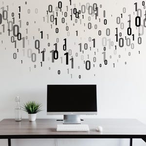 Może przedstawiać: Czarny monitor komputerowy z białą klawiaturą i białą myszką na szarym drewnianym biurku. Ściana za biurkiem jest biała z wzorem czarnych i szarych cyfr.