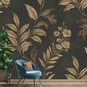 May include: Dark gray wallpaper with a repeating pattern of gold-colored leaves and flowers. A teal chair with a brown pillow sits in front of the wallpaper. A potted plant is to the left of the chair.