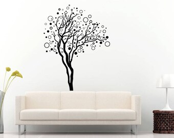 Könnte beinhalten: Schwarz-weiße Wanddekoration eines stilisierten Baumes mit einem Kreis-Muster. Der Baum befindet sich an einer weißen Wand mit einem weißen Sofa davor.
