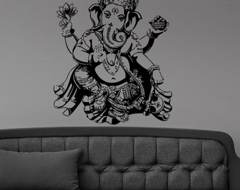 May include: Black and white silhouette wall decal of the Hindu deity Ganesha, sitting with his trunk raised and holding a lotus flower and a bowl of sweets.