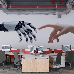 May include: An office interior with desks, computers, and chairs. A mural shows a robotic hand extending towards a human hand. The image conveys a theme of technology and human interaction.