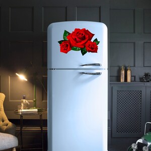 Puede incluir: Un refrigerador blanco con una calcoman&iacute;a de rosa roja en la puerta. El refrigerador tiene un compartimento congelador en la parte superior y un compartimento inferior para almacenar alimentos.