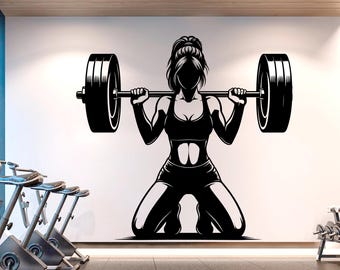May include: Black and white silhouette of a person lifting a barbell. The person is wearing a sports bra and shorts. The barbell is above their head.