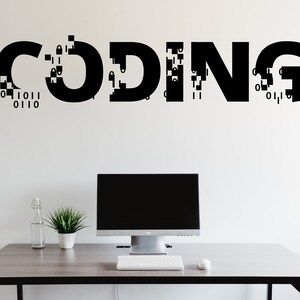 May include: A white wall with the word "CODING" written in black letters with a pixelated effect. A computer monitor, keyboard and mouse are on a grey desk in front of the wall.