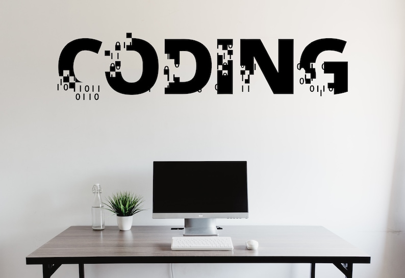 May include: A white wall with the word "CODING" written in black letters with a pixelated effect. A computer monitor, keyboard and mouse are on a grey desk in front of the wall.