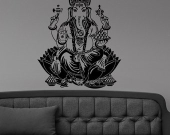 May include: Black and white silhouette wall decal of the Hindu deity Ganesha sitting on a lotus flower. Ganesha is depicted with an elephant head, four arms, and a large belly. He is holding a variety of objects in his hands, including a sweet, a book, and a lotus flower.