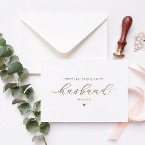 Personalized wedding day card reading “Today I Get to Call You My Husband” in rose gold foil with custom wedding date, modern minimalist bride to groom wedding card styled flat lay with envelope, ribbon, and eucalyptus.