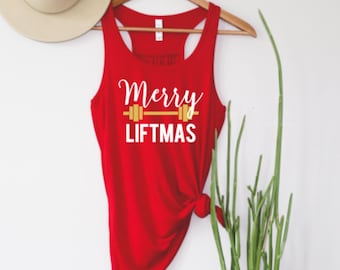May include: Red tank top with a white graphic that says "Merry Liftmas" with a gold dumbbell above the text.