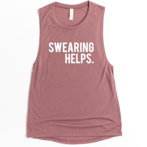 May include: A sleeveless, dusty rose-colored tank top with the white text "SWEARING HELPS." The shirt has a scoop neck and a relaxed fit. This casual top is suitable for workouts or everyday wear.