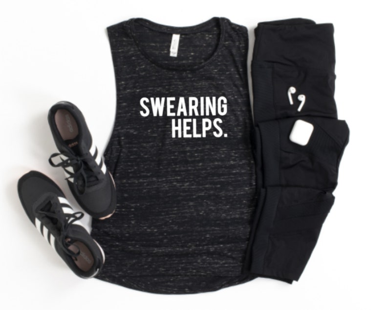 May include: A black and white marbled tank top with the text "SWARING HELPS." is displayed next to black athletic leggings, a pair of black sneakers with white stripes, and a pair of white wireless earbuds and a charging case.