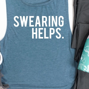 May include: A blue-green tank top with the text "SWEARING HELPS." in white block letters. The sleeveless shirt is paired with dark gray leggings and a teal and white patterned item.