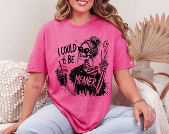 May include: A hot pink t-shirt with a black graphic of a skeleton wearing sunglasses, holding a drink, and flashing a peace sign. The text on the shirt reads "I COULD BE MEANER".