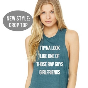 May include: A teal blue crop top with the text "Tryna look like one of those rap guys girlfriends" printed in white.