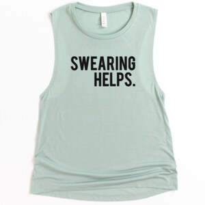 May include: A sleeveless, light green tank top with the phrase "SWEARING HELPS." printed in bold, black letters. The shirt has a rounded neckline and a slightly gathered side seam.
