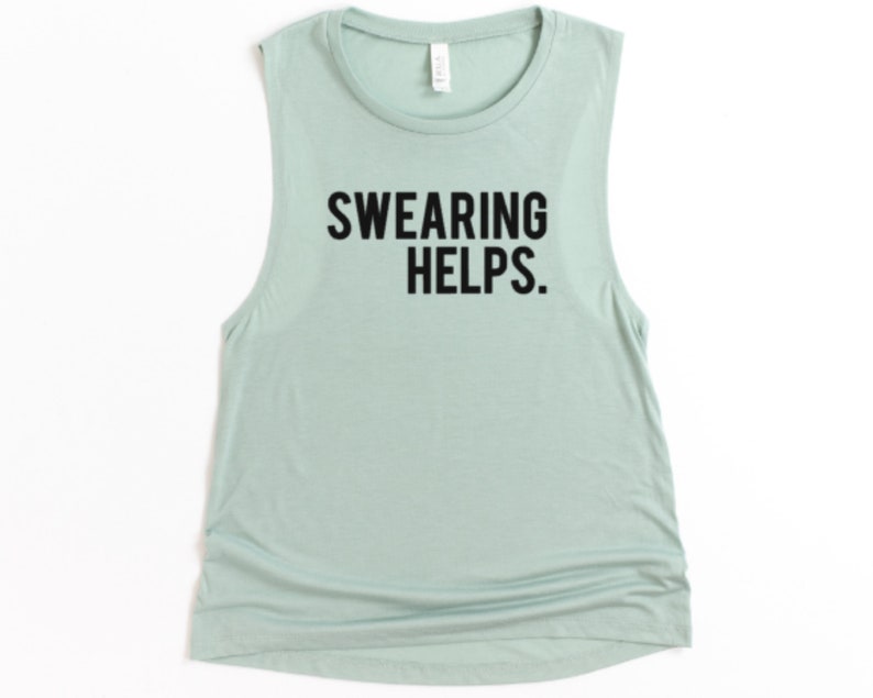 May include: A sleeveless, light green tank top with the phrase "SWEARING HELPS." printed in bold, black letters. The shirt has a rounded neckline and a slightly gathered side seam.