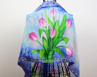 Könnte beinhalten: Handgemalter Seidenschal mit einem Strauß rosa Tulpen mit grünen Blättern auf blauem Hintergrund. Der Schal wird auf einem schwarzen Ständer präsentiert. Der Text "Hand painted silk by Joanna Aleksandrova" ist oben im Bild sichtbar.