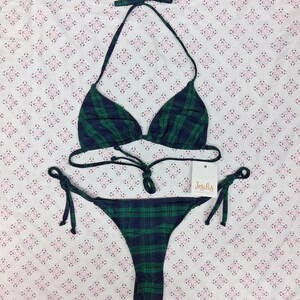 May include: A two-piece bikini set featuring a dark green and navy blue plaid pattern. The top has triangle cups with thin halter straps and a tie closure. The bottom features side ties for an adjustable fit. A white tag with the text Jesilis is attached.