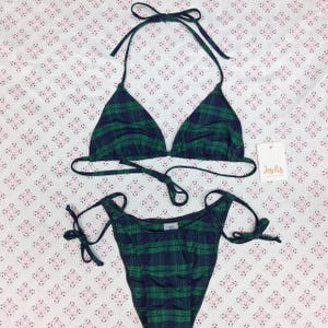 May include: A two-piece bikini set featuring a dark green and navy blue plaid pattern. The top is a triangle style with adjustable halter neck and back ties. The bottom features side tie closures. A white tag with the text Jesilis is attached.