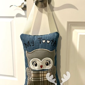 May include: A blue denim tooth fairy pillow with an embroidered owl design. The pillow has a pocket for teeth and says "My Teeth" on the front.