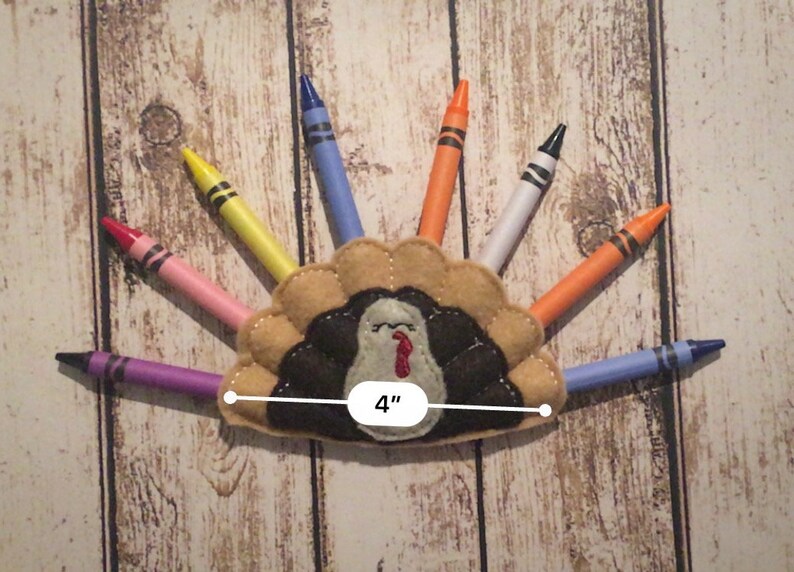 Puede incluir: Un porta l&aacute;pices de fieltro con forma de pavo con un cuerpo marr&oacute;n, plumas negras y una barbilla roja. El porta l&aacute;pices tiene 10 cm de ancho y tiene ocho l&aacute;pices que sobresalen. Los l&aacute;pices son morado, azul, blanco, naranja, amarillo, rosa y rojo.