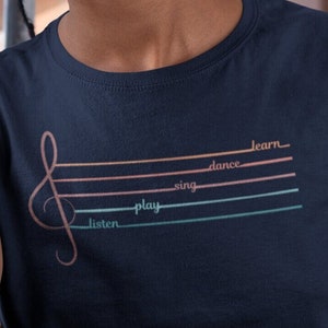 May include: A navy blue t-shirt with a treble clef graphic and the words "listen", "play", "sing", "dance", and "learn" written on the lines of the staff.