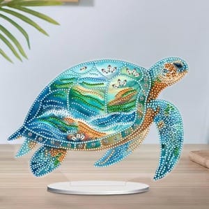 May include: A white ceramic mug with a black handle and the text "But First, Coffee" in a black, handwritten-style font. The mug is on a white surface.