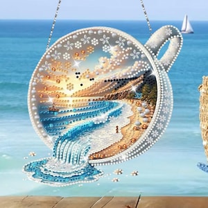 Può includere: Una scena di spiaggia decorativa sospesa a forma di tazza da tè. L'opera d'arte presenta una vista dettagliata sull'oceano con una spiaggia sabbiosa, onde e una piccola barca. Il bordo e il manico della tazza sono adornati con motivi floreali e a pois, su uno sfondo blu.