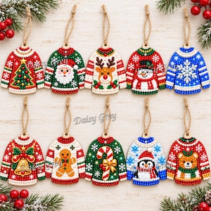 Puede incluir: Diez adornos navideños con forma de suéter y diseños de arte de diamantes que incluyen un árbol, Santa, reno, muñeco de nieve, copo de nieve, campana, hombre de jengibre, bastón de caramelo, pingüino y oso. Cada uno tiene un lazo de yute.