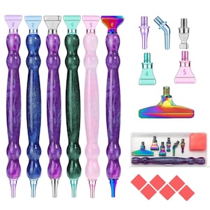 May include: Set of six diamond painting tools with different colored handles and tips. The tools are made of metal and have a sparkly finish. The set also includes a variety of tips, a sponge, and a tray for holding diamonds.
