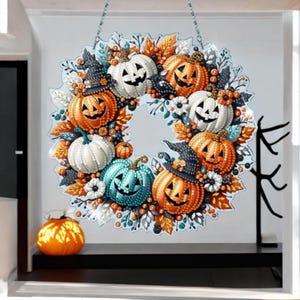 Può includere: Una ghirlanda circolare di Halloween con diverse zucche intagliate in arancione, bianco e turchese, decorate con cappelli da strega neri, foglie autunnali e piccoli fiori. L'elemento decorativo è appeso a una catena argentata e presenta una texture.