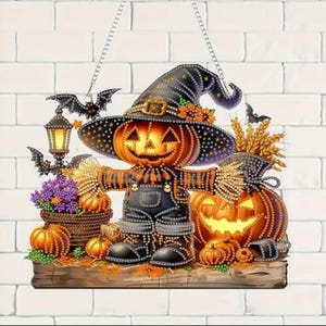 Può includere: Una decorazione da appendere in diamond painting raffigurante uno spaventapasseri con testa di zucca luminosa, cappello da strega nero e salopette. La scena include una lanterna, pipistrelli, fiori viola in un cesto, spighe di grano e zucche.