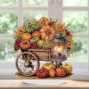 May include: A decorative wooden cart display featuring a collection of orange, green, and yellow pumpkins, sunflowers, and red berries. A metal lantern with a glowing light sits on the cart, surrounded by additional pumpkins on the base.