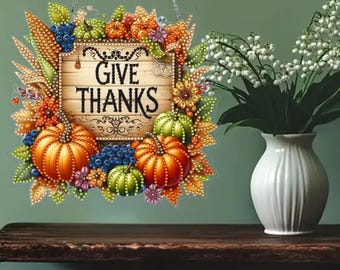 May include: A decorative wooden sign with the words "GIVE THANKS" in black lettering. The sign is surrounded by a colorful arrangement of pumpkins, corn, berries, and fall foliage. The sign is hanging from a silver chain.