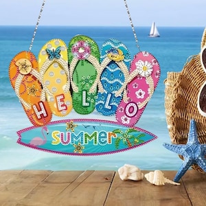 Op de afbeelding: Een kleurrijk houten bord met het woord 'HELLO' op vijf slippers. De slippers zijn oranje, geel, groen, blauw en roze. Onder de slippers staat een surfplank met het woord 'summer' en een flamingo-afbeelding.