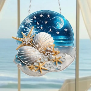 Può includere: Decorazione rotonda a tema spiaggia, con conchiglie, stelle marine e perle. Lo sfondo presenta un cielo notturno con stelle e una luna crescente, e una scena di spiaggia. Appesa a una catena.