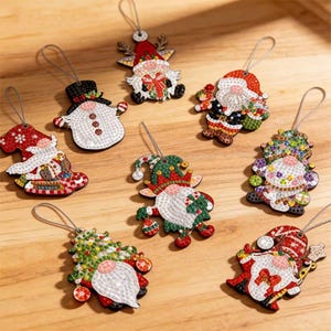 Könnte beinhalten: Eine Sammlung von acht Diamond-Painting-Anhängern mit verschiedenen weihnachtlichen Motiven wie Gnomen, einem Schneemann und dem Weihnachtsmann. Jeder Anhänger ist mit bunten facettierten Steinchen besetzt und hat eine silberne Schlaufe.