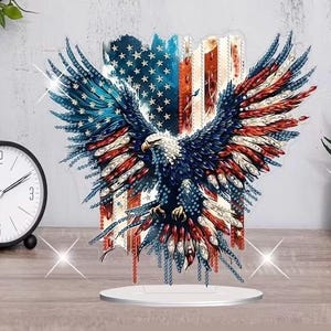 May include: A patriotic acrylic eagle sculpture with outstretched wings, featuring the American flag's colors: red, white, and blue. The eagle is mounted on a white circular base, suitable for display on a desk or shelf.