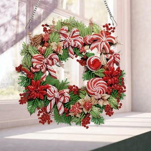 May include: A circular holiday wreath featuring green pine needles, red berries, and white and red striped bows. The wreath is decorated with red and white peppermint candy ornaments and poinsettia flowers, suspended by a silver metal chain.