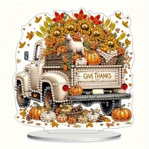 May include: A decorative fall-themed truck figurine. The white truck bed is filled with sunflowers, pumpkins, and a white goat. The truck bed reads "GIVE THANKS". The figurine is on a clear base.