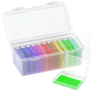 Puede incluir: Una caja de almacenamiento de plástico transparente con tapa abatible, llena de pequeñas cuentas de colores en varios tonos. Cada compartimento está etiquetado con un número. Una bandeja más pequeña y abierta con una rejilla verde está en primer plano. La caja está diseñada para organizar suministros de manualidades.